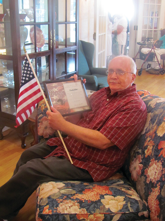 Gordon Dutra, a resident at The Bridge at Cherry Hill who served in the United States Army, holds an American flag and the certificate he received from members of the 107th Signal Company during Monday’s Veterans Day salute.