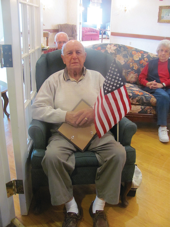 Armando “Casey” Farnesi, 85, who served with the U.S. Army in the Korean War, holds his American flag during the singing of “God Bless America.”