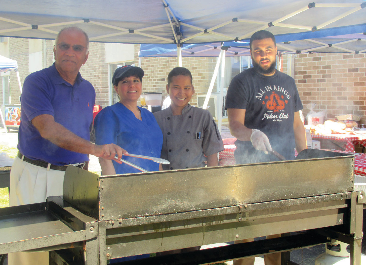 DELIGHTFUL DUTY: Akshay Talwar, left, owner and CEO of the Briarcliffe Campus, joins staffers Sharon Botelho, Henary Yan and Brian Razzino at the grill during Friday’s old-fashioned cookout.