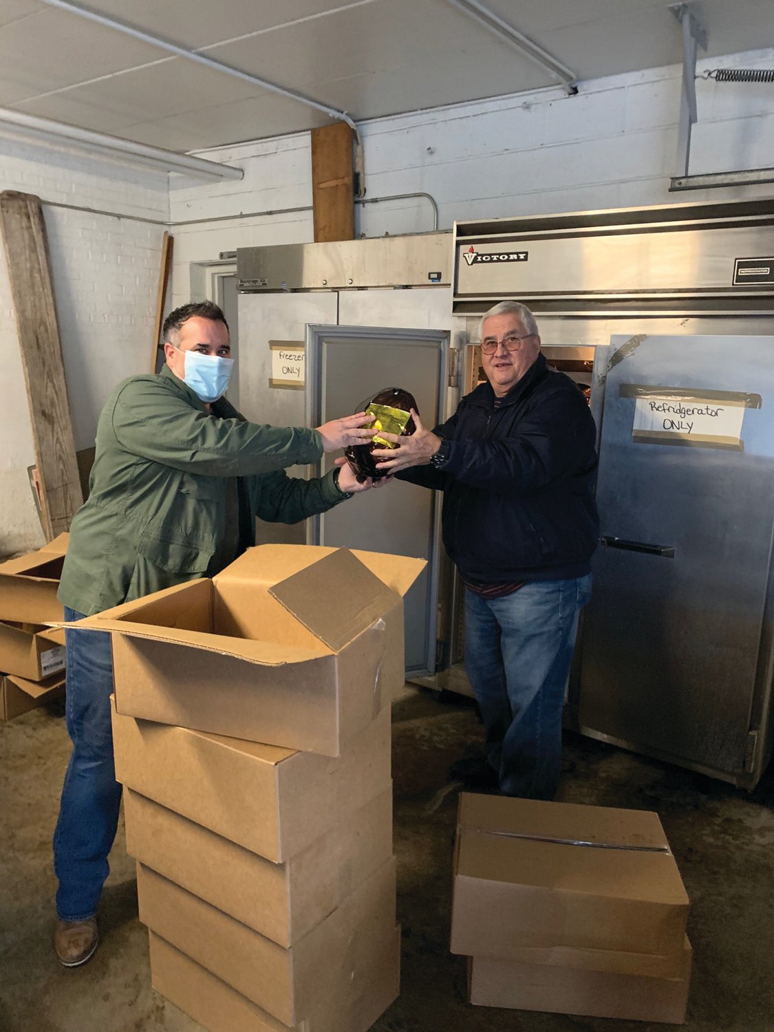 HOLIDAY HAPPENING: Pannese Society Warden Jason Parenteau gives one of 36 hams – as well as three-dozen gift cards – that Our Lady of Grace Church official Joseph Quartino then delivered to different families in need for Christmas.