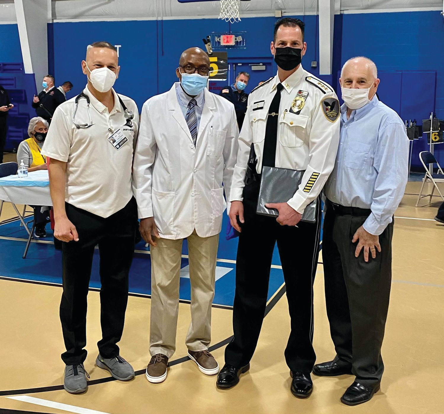 CALL ANSWERED: The Rev. Dr. Christopher Abhulime (second from left) helped provide vaccination shots during last week’s vaccination clinic held at the Indoor Recreation Center. He is joined by Dr. Brian Kwetkowski, Johnston Police Chief Joseph Razza and Mayor Joseph Polisena.