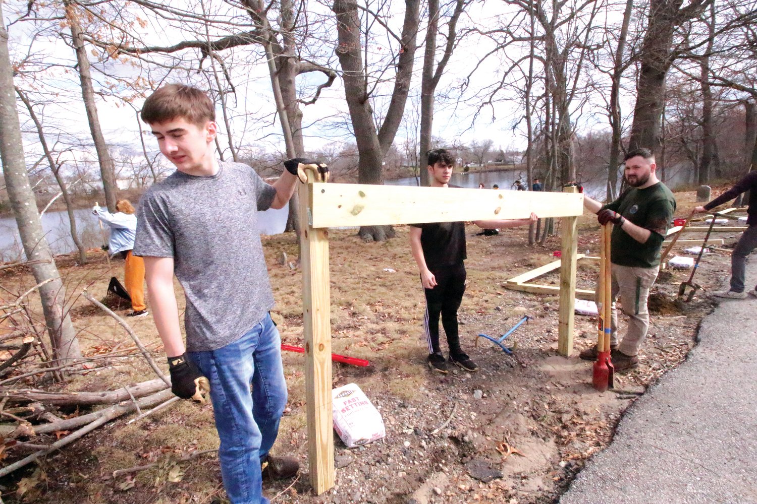 POSITIONING:  Peter Masse looks to position one of ten guardrails he and fellow Scouts -- along with the help of former Scouts, friends and parents -- erected Saturday to prevent people from parking in Warwick Historic Cemetery #9. (Warwick Beacon photos)