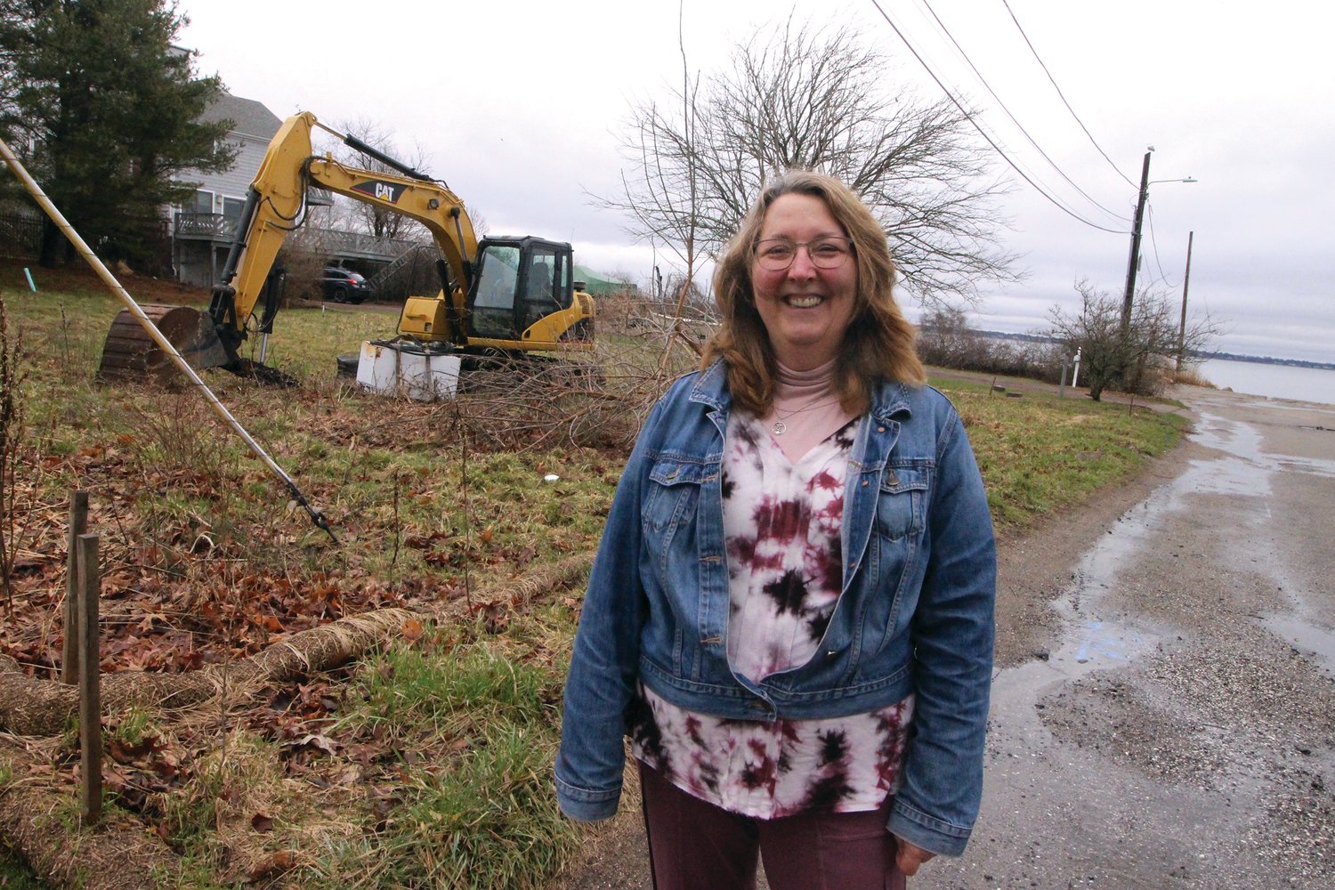 A CAT NEXT DOOR: Jeanne Mutokyle and  the Caterpillar that has been is the adjoining lot for months. (Warwick Beacon photo)