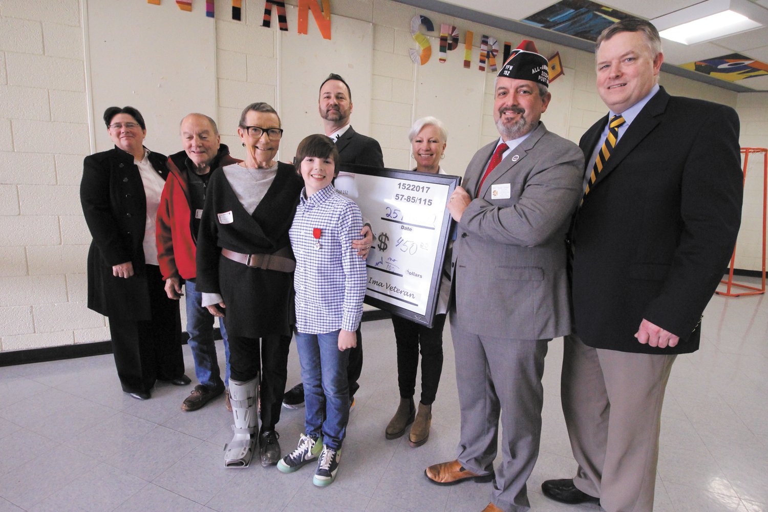 STATE ESSAY WINNER:  Winman Middle School seventh grader Harry Fallon, center, was honored last week by the VFW for his winning essay on “What makes a good America.” He is pictured with from left: Judith Cobden, chair of the Warwick School Committee; his grandparents, Anthony and Asa Orsino; Winman Principal Adam Heywood, his mother Samantha Fallon; RI representative on the VFW National Board of Directors Eric Dukat and Assistant Superintendent William McCaffrey. (Warwick Beacon photo)