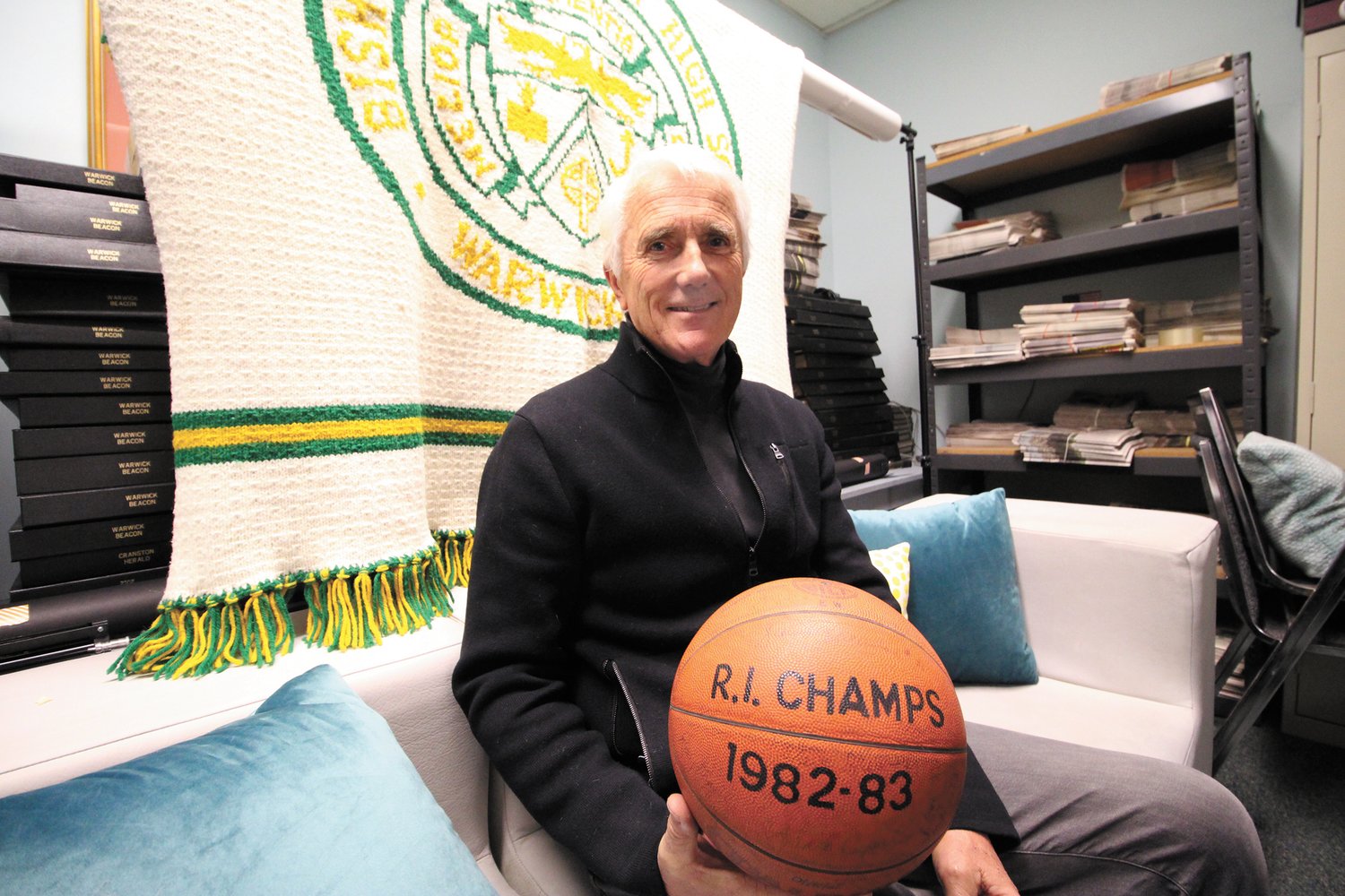 FOR AUCTION AGAIN: Tom Lynch with the ball signed by the 1983 Bishop Hendricken basketball state champs that he won in the Epoch auction in 1983 and he’s returning to the school to be auctioned at this year’s Epoch on April 30.  Behind him is the hand-knitted blanket that he is also returning to be auctioned again. (Warwick Beacon photo)