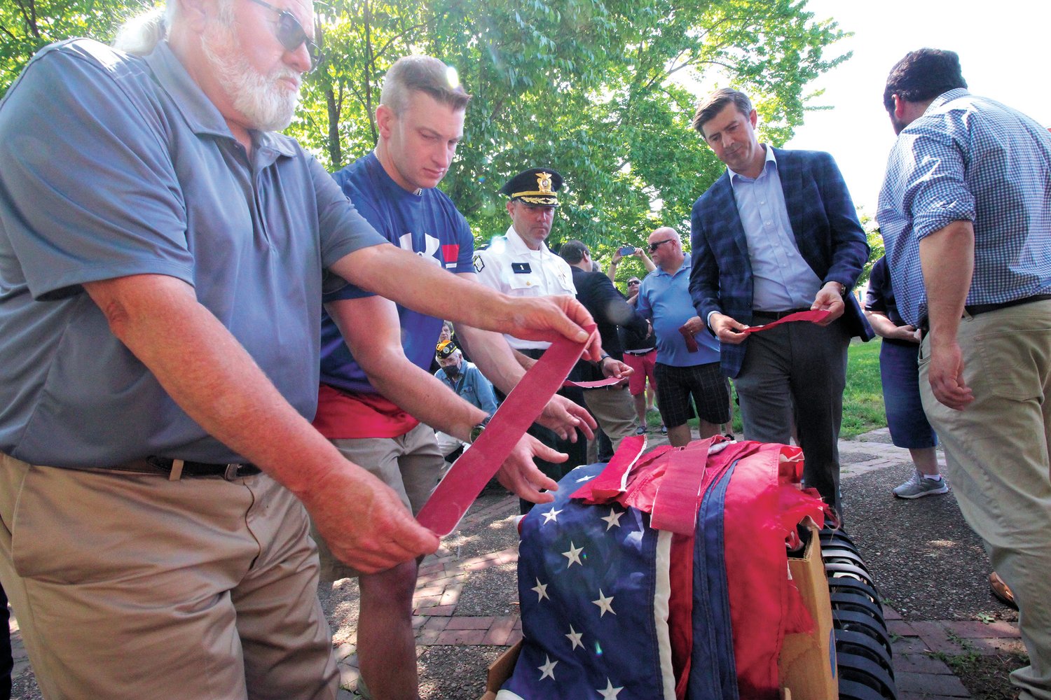 REITRING THE FLAG: From left Rep. David Bennett, Rep. Evan Shanley, Col. Bradford Connor and Matt LaMountain place tattered flag remians on a pile of flags to be reitred by incinaration.