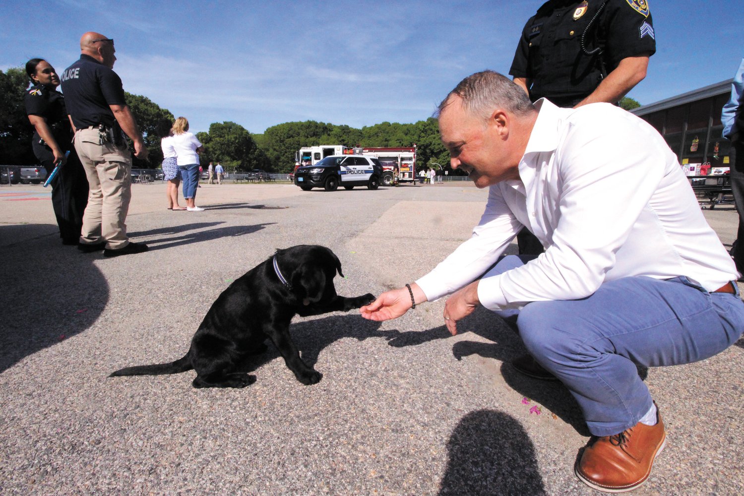 MEETING THE YOUNGEST DEAPRTMENT MEMBER: Dan Scanlon Jr, gets a paw shake from Charley, the newest Police Department recruit on May 25.