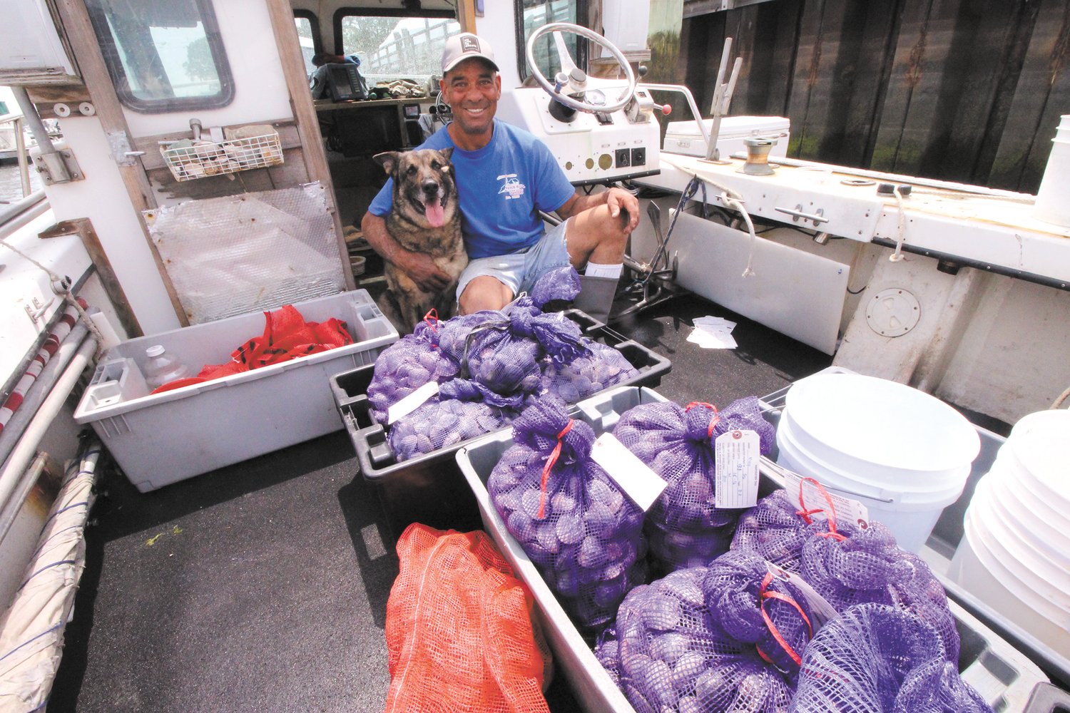 BUSHELS OF LITTLE NECKS: Jody King who is almost always accompanied by his dog Nosmo prepares to off load Tuesday’s catch after returning to the marina in Oakland Beach.  (Warwick Beacon photos)