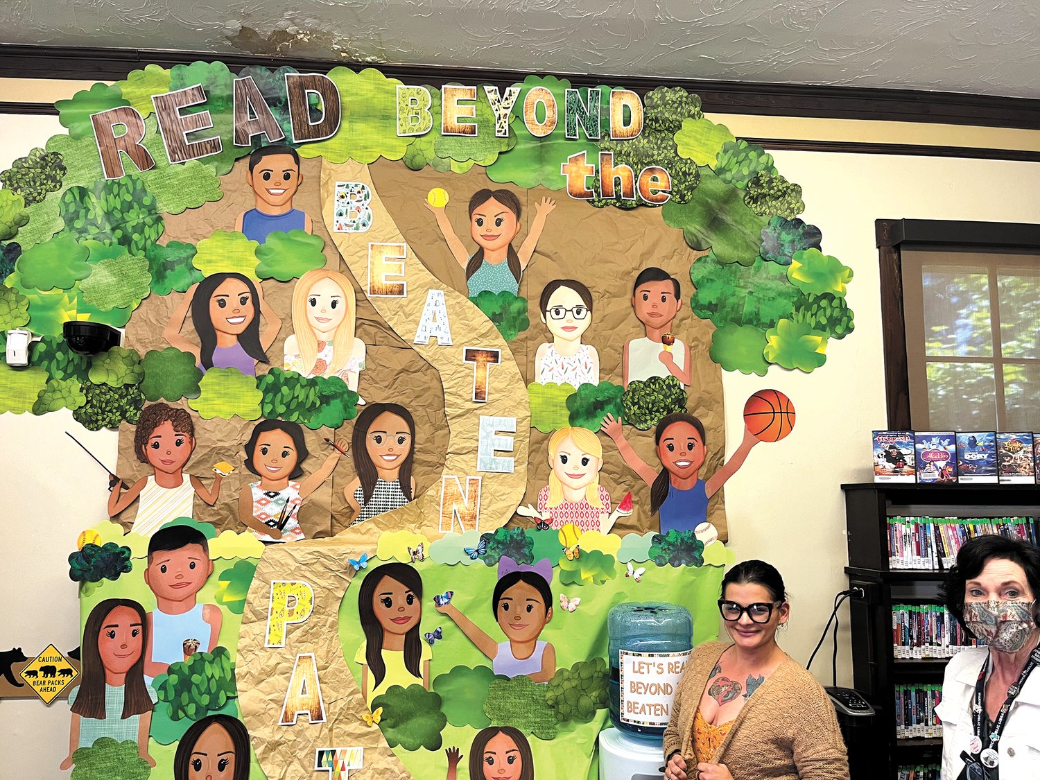 PATH TO SUMMER READING: Norwood Branch Library manager Tina Travis stands beside the display she made to inspire summer reading featuring the 19 children who lost their lives in the mass shooting in Uvalde Texas on May 24. (Warwick Beacon photo)