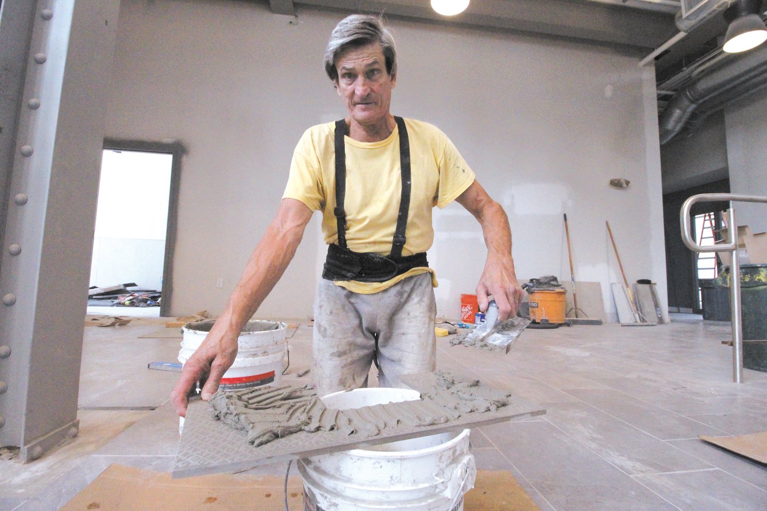 MADE TO FIT: Rick Perry of Perry Tile prepares to fit one of the floor tiles for the atrium that will give on to city annex and AAA offices when completed.  Perry has run the business for 38 years. His son, Brandon is also part of the business.