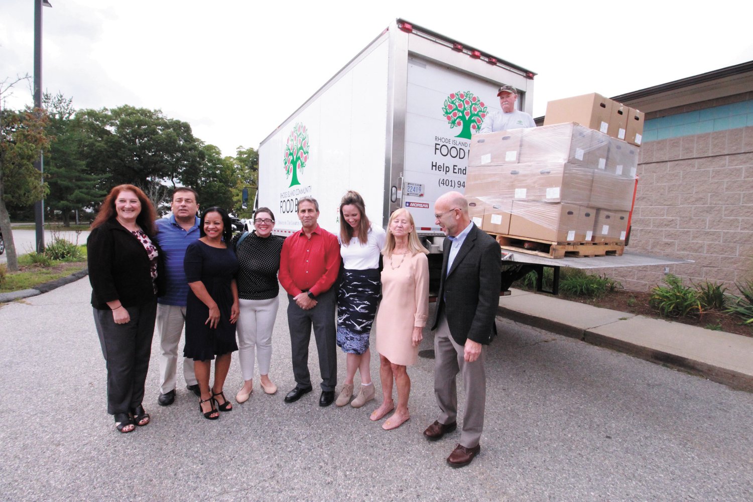 BOX DROP OFF: Officials with Mayor Frank Picozzi in the center  gather for a group photo outside the Pilgrim Senior Center as a Rhode Island Community Food Bank pulls up to deliver food boxes for distribution.