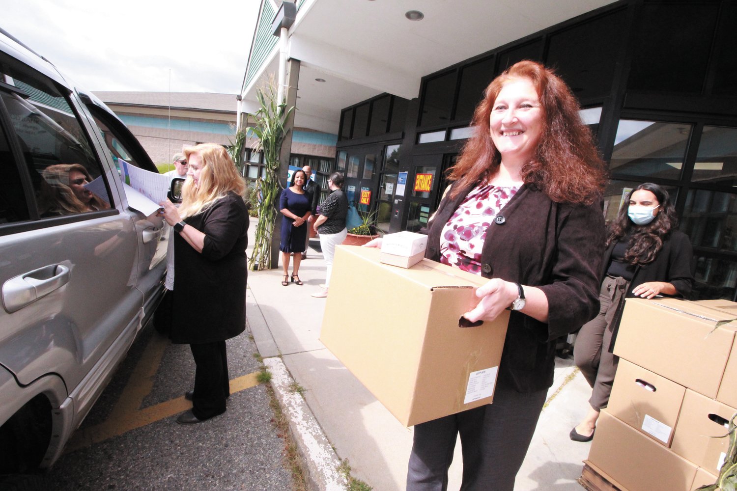 AT SENIOR CENTER PICKUP:  Maria Cimini, director of the Healthy Aging, hoists a box during the monthly pickup held last week as Patricia Almonte, who coordinates the center program, takes information from the recipient. (Warwick Beacon photos)
