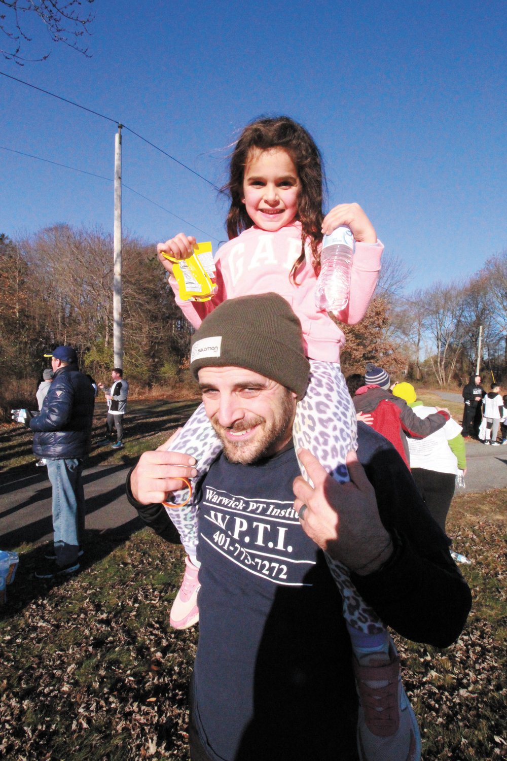 ON DAD’S SHOULDERS: Physical therapist Dan Forlasto, who has conducted the warmup for trot participants since the event started, hoisted his daughter Ella at the finish line.