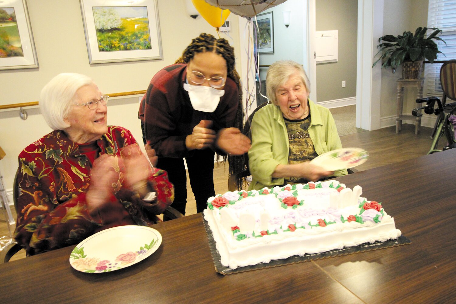 SAVING THEIR BREATH: With the use of paper plates provided by Taniesha Sellers, Annette and Evaline swished out the candles on their cake celebrating a combined 205 years. (Warwick Beacon photos)